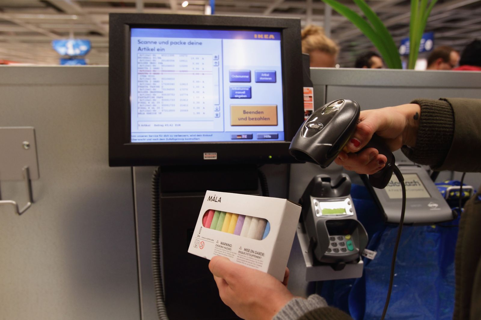A photo of a person using a self checkout machine in a store.